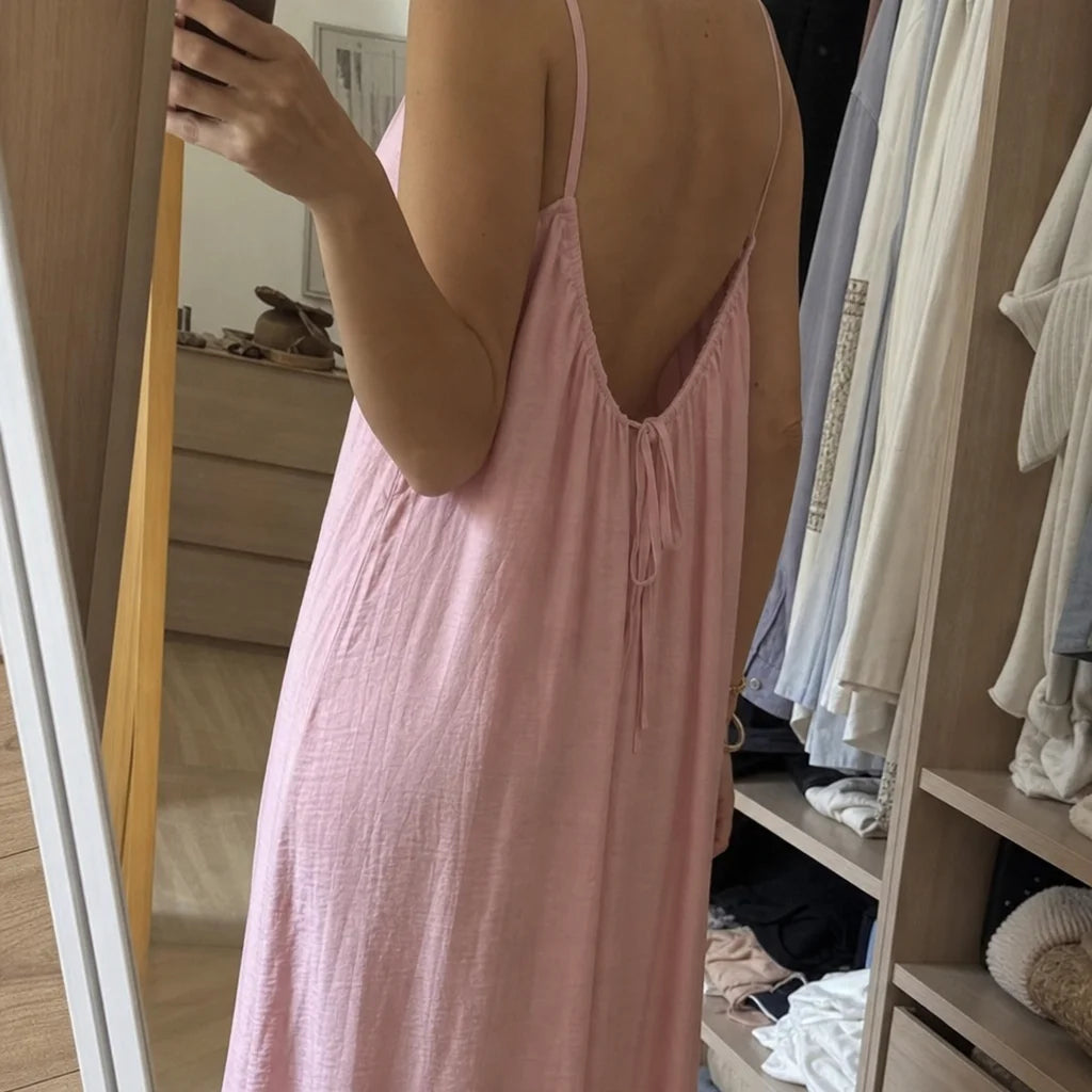 Real customer-worn fashion photograph, 1:1. Frame a partial mirror view of the exact pale pink Vesti